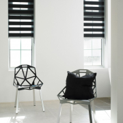 Room with two chairs and two windows with lumen blinds 