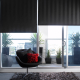 Dark gray roller blinds half open with a red lamp and black chair with red pillows